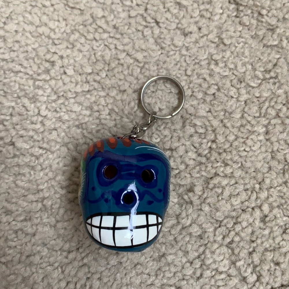 Mexican ceramic keychain of skull with painted decoration.